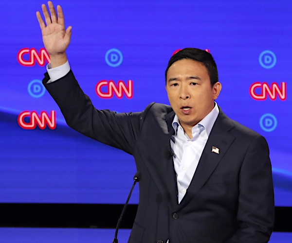 andrew yang raises his right hand to answer a question during the democratic presidential primary debate