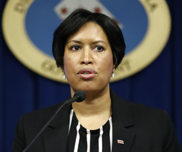 muriel bowser is shown in black and white attire speaking to the media