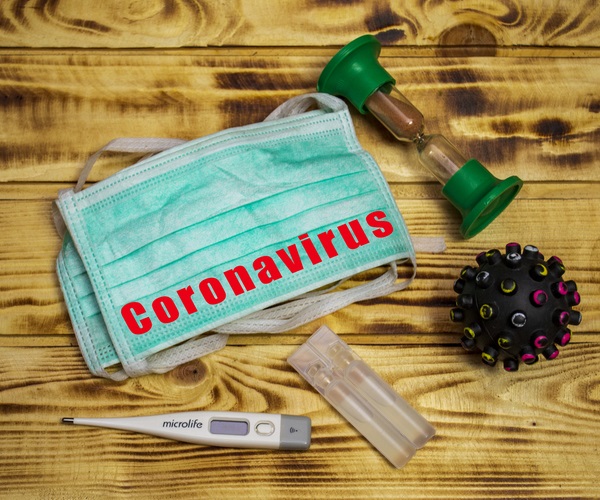 Coronavirus quarantine concept, on a wooden background, medical mask with capsule and virus