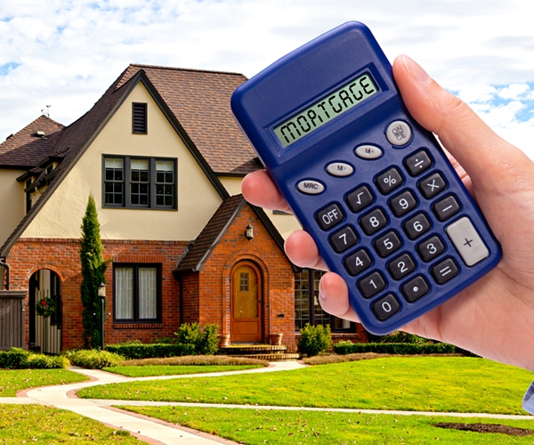 hand holding calculator in front of home