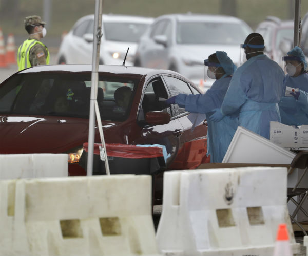 people in medical protective gear administer covid-19 tests