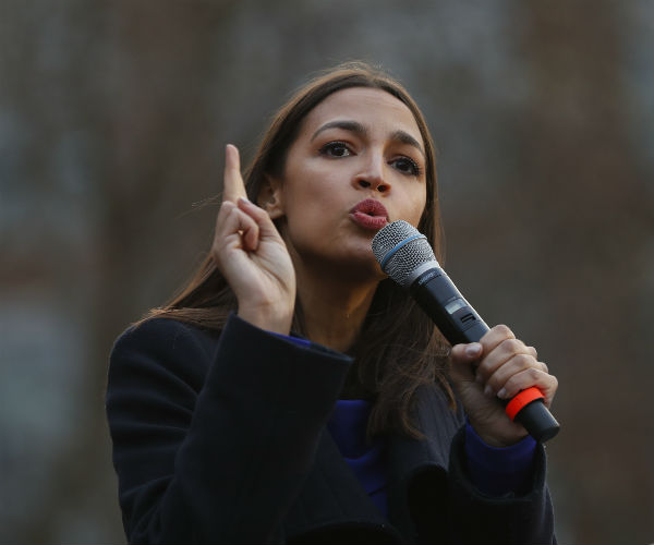 aoc is shown holding a mic speaking at a campaign rally