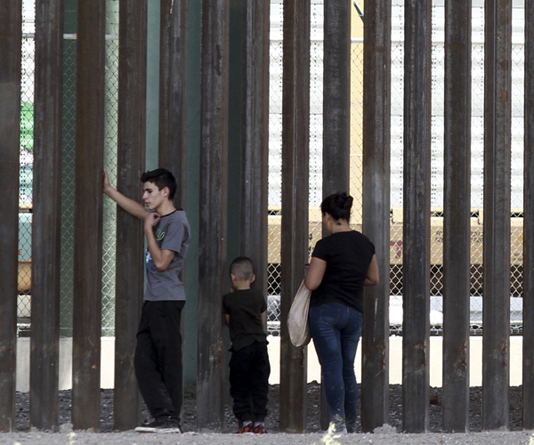 Illegal migrants wait for Border Patrol along a wall in Texas