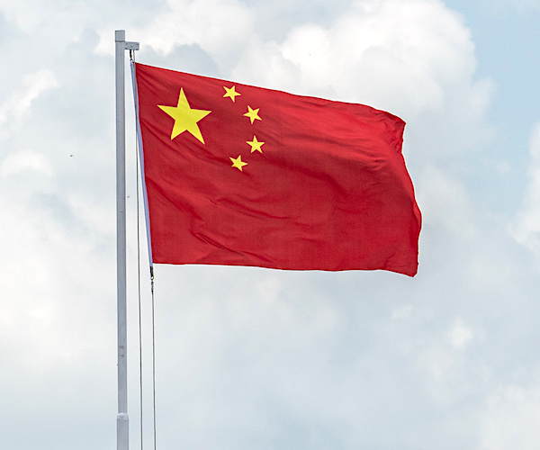 the china flag waves before a partially cloudy sky
