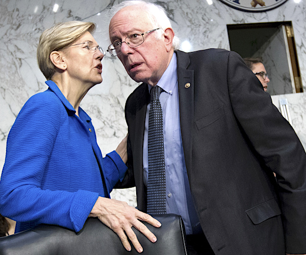 Elizabeth Warren leans in to speak into the ear of Bernie Sanders