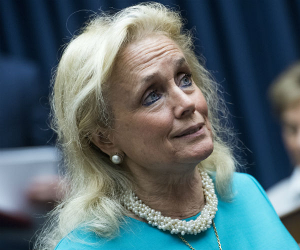 debbie dingell is shown in a teal suit and twisted pearl necklace