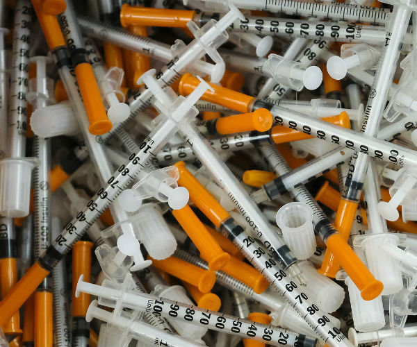 a pile of needles and syringes sitting in a box